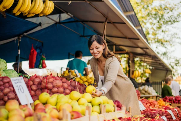 Женщина на рынке, ищет фрукты — стоковое фото