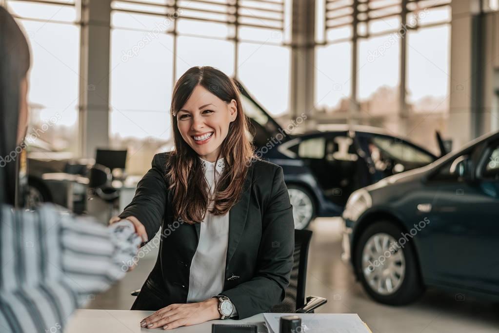 saleswoman shaking hands with customer.