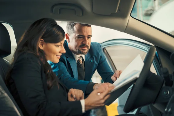 Autohändler zeigt Geschäftsfrau Vertrag — Stockfoto