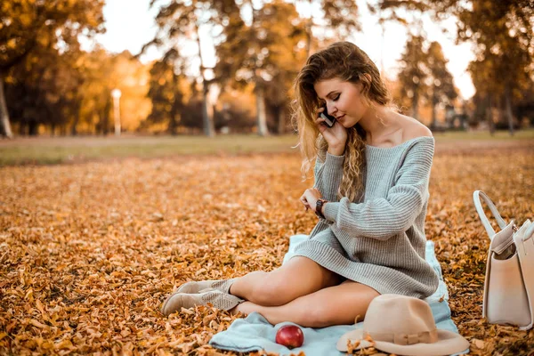 Mujer de moda sentada en un parque de otoño —  Fotos de Stock