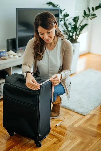 Woman traveler measuring her luggage