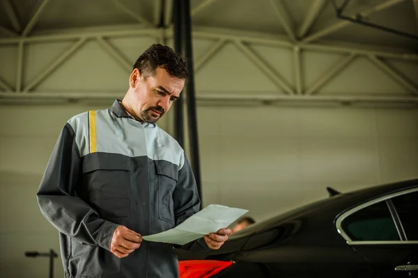 Mechanic looking at paper — Stock Photo, Image