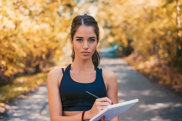 Mujer escribiendo plan de entrenamiento . — Foto de Stock