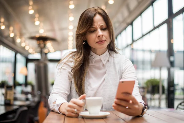 Kadın telefonu kafede mesajı okuma.