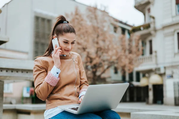 Vrouw met behulp van haar laptop en mobiele telefoon — Stockfoto