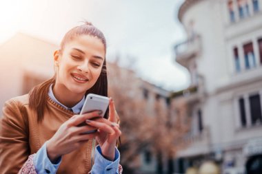 Akıllı telefon kullanan genç bir kadın.