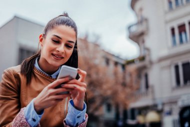 Akıllı telefon kullanan genç bir kadın.