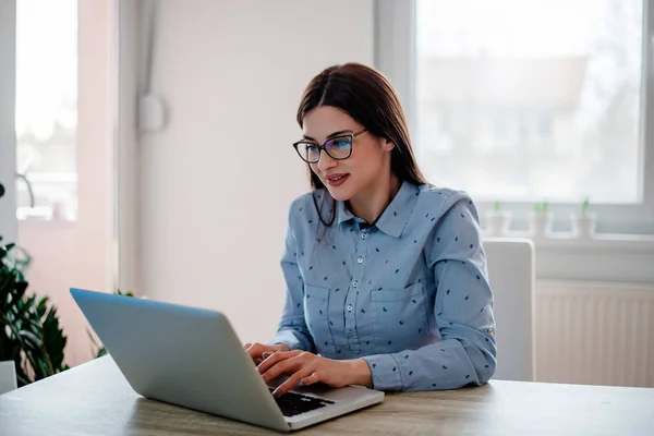 Chica con gafas de vista usando el ordenador portátil en casa —  Fotos de Stock