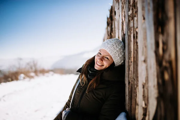 Smiling woman leaning against old wooden wall
