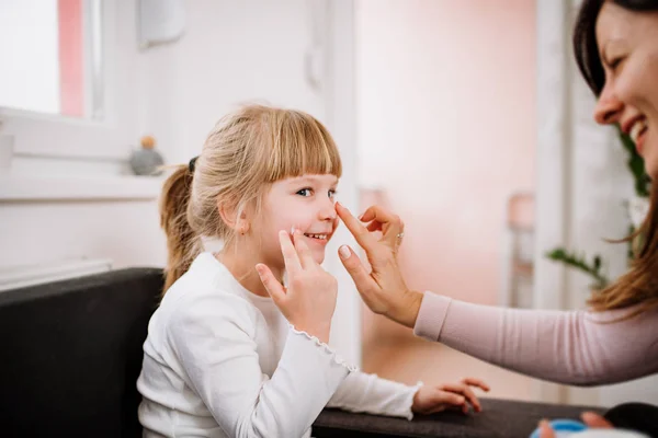 Lachende Moeder Crème Aanbrengen Gezicht Van Dochtertje — Stockfoto