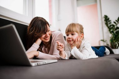 Sevimli küçük kız annesi ile çizgi film izlerken laptop ekranında işaret.