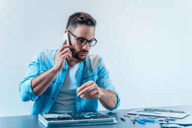 Laptop tamir ederken bir cep telefonu üzerinde konuşurken bilgisayar teknisyeni.