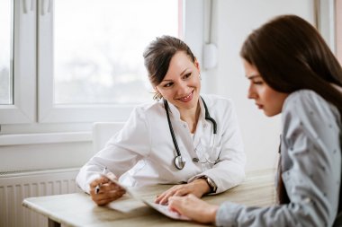 Büyüleyici kadın doktor iyi sınav sonuçlarını bir kadın hastaya veriyor.