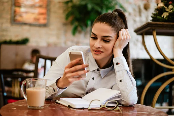 Uma Jovem Ler Livro Café Usando Telefone Celular — Fotografia de Stock