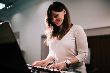 Synthesizer piyano çalan sevimli genç kadın.