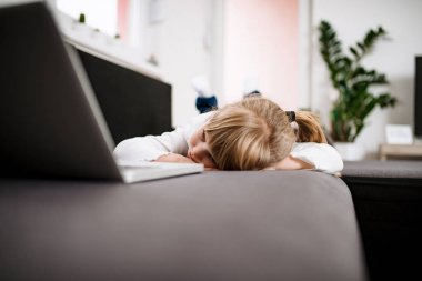 Küçük kız uyuya kanepede dizüstü bilgisayarda çizgi film izlerken.