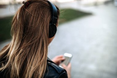 Kız müzik dinleme arkadan görünüş kulaklıklar açık havada.