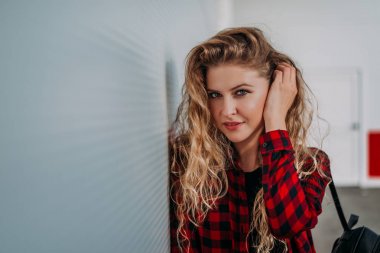 Duvara yaslanmış moda sarışın kadın portresi.