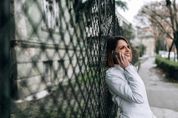 Красивая Молодая Женщина Опирается Проволочный Забор Разговаривает Мобильному Телефону — стоковое фото
