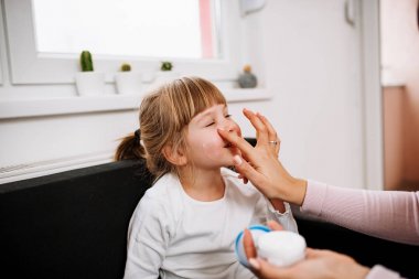 yüz kremi küçük kızı üzerine koyarak anne