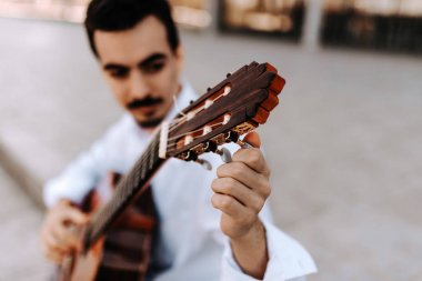 Genç adam şehir sokakta akustik gitar çalmak