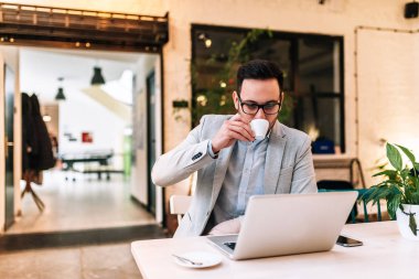 Dizüstü bilgisayarda çalışan takım elbiseli genç işadamı