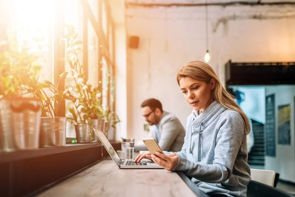 Two young people sitting in cafe and working on laptop