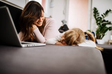 Küçük kız annesi ile film izlerken kanepede uyuya.