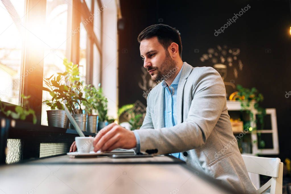 Entrepreneur drinking a cup of coffee while working at the cafe 