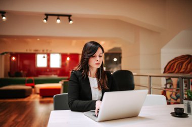 Bir dizüstü bilgisayarda çalışan ciddi kadın portresi.