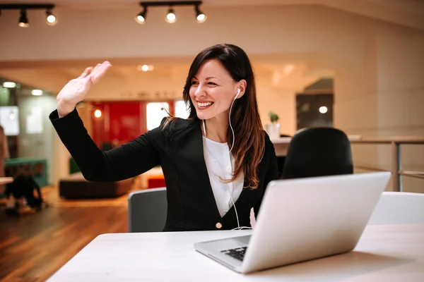 Beautiful businesswoman gesturing sitting in front of laptop.