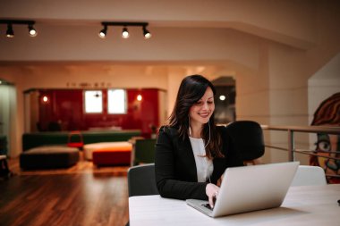 Kafede dizüstü kullanarak kulaklık ile genç gülümseyen kadın