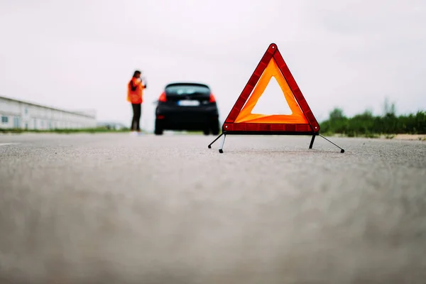 Piros Figyelmeztető Tiangle Előtérben Úton Lány Fényvisszaverő Mellény Háttér — Stock Fotó