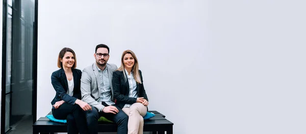 colleagues sitting at wooden bench together in office, business team concept