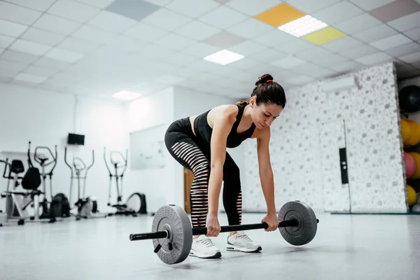 sporty woman with barbell doing weight lifting workout at gym