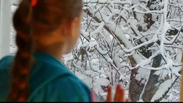 Het Meisje Kijkt Uit Het Raam Dalende Sneeuw — Stockvideo