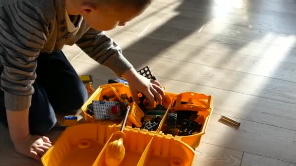Мальчика играет дизайнер. Детская игра. Ребенок складывает пластиковый дизайнер . — стоковое видео