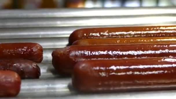 A hot dog kolbász fűtött. Készül a francia hot kutya. Spinning a grill kolbász. Fast food — Stock videók