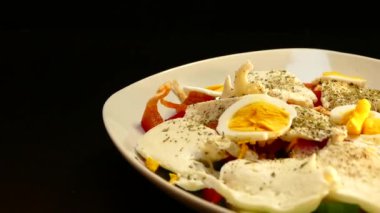 Salata sebze ve tavuk yumurta zeytinyağı ile dökülür. Siyah bir zemin üzerine gıda.