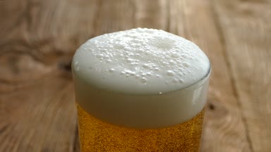 Taze bira cam ahşap bir masa üzerine dökün. Bira köpük bardaktan dökülür. Lşığını masada.