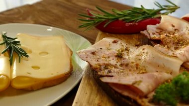 Sandviç sosis ve peynir ile. Siyah ekmek pastırma ve baharatlar ile. Plaka üzerinde delikli peynir. İnce dilimlenmiş domuz eti