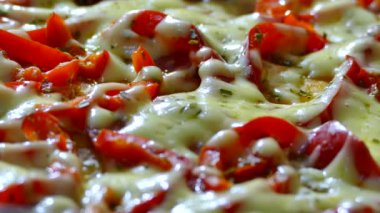 Kırmızı biber ve peynir bir fincan bir tavada hazırlanır. Bir tavada peynirli pizza serpilir.