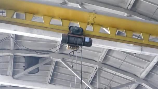 Ein Kran mit Seilwinde bewegt sich in der Fabrikhalle. Seilwinde mit Ketten bewegt sich auf Schienen. — Stockvideo