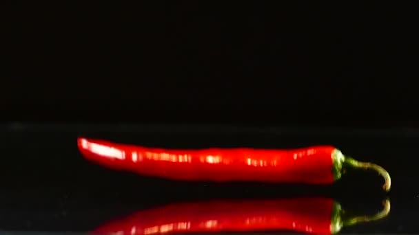 Le piment rouge tombe lentement sur la table. 4 poivrons sur la table de cuisine. Nourriture très épicée .