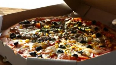 Bir kutu içinde pizza teslimi. Lezzetli sulu ve güzel pizza yuvarlak bıçakla kesilir. Aile mantar, zeytin, peynir ve domates pizza yiyor.