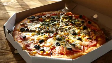 Bir kutu içinde pizza teslimi. Lezzetli sulu ve güzel pizza yuvarlak bıçakla kesilir. Aile mantar, zeytin, peynir ve domates pizza yiyor.