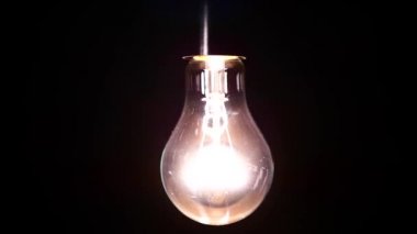 Akkor lamba ile tungsten filaman tel üzerinde wobbles. Işık yanıp söner nedeniyle fakir bir kişi. Elektrik enerjisi odaya kayboldu. Bir ampul ışığı. Ampul yakın çekim.