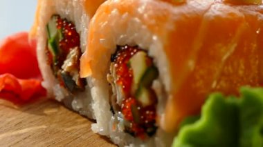 Lezzetli ve iştah açıcı suşi. Suşi somon ve taze salatalık dilimleri ile. Bir ahşap tahta üzerinde kırmızı zencefil ve yeşil wasabi suşi servis. Suşi kırmızı ejderha