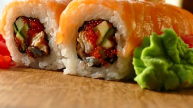 Lezzetli ve iştah açıcı suşi. Suşi somon ve taze salatalık dilimleri ile. Bir ahşap tahta üzerinde kırmızı zencefil ve yeşil wasabi suşi servis. Suşi kırmızı ejderha