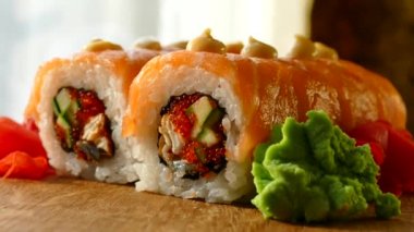 Lezzetli ve iştah açıcı suşi. Suşi somon ve taze salatalık dilimleri ile. Bir ahşap tahta üzerinde kırmızı zencefil ve yeşil wasabi suşi servis. Suşi kırmızı ejderha